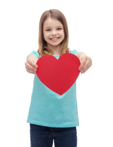 smiling little girl giving red heart